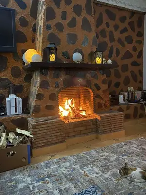 a brick fireplace with a fire in it at Suite avec salle de bain privée das un beau Riad avec piscine in Aghmat