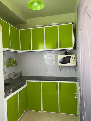 a green kitchen with green cabinets and a microwave at appart près du stade de fes in Fès