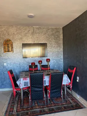 a dining room with a table and chairs on a rug at appart près du stade de fes in Fès