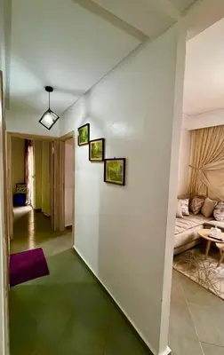 a living room with a white wall with three pictures on it at A Comfortable & Modern Apartment Mhamid Marrakech in Oulad Akkou