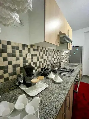 a kitchen with a counter top with white chairs at A Comfortable & Modern Apartment Mhamid Marrakech in Oulad Akkou
