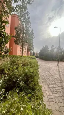 a cobblestone street with bushes and a building at A Comfortable & Modern Apartment Mhamid Marrakech in Oulad Akkou