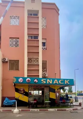 a pink building with a snack sign in front of it at A Comfortable & Modern Apartment Mhamid Marrakech in Oulad Akkou