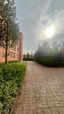 a brick road with a building and a tree at A Comfortable & Modern Apartment Mhamid Marrakech in Oulad Akkou
