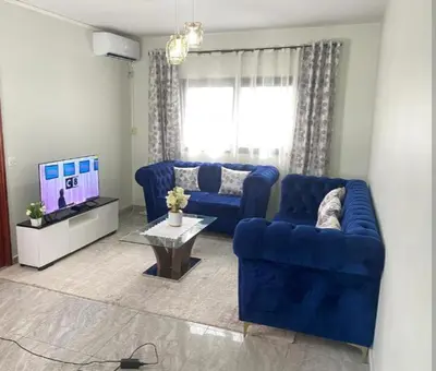 a living room with a blue couch and a tv at Moussa in Oulad Akkou
