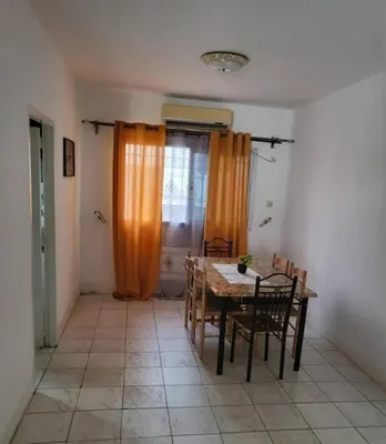 a dining room with a table and chairs and an orange curtain at Moussa in Oulad Akkou