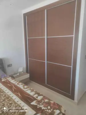 a large wooden closet in a room with a bed at Snensnsnsnsnhxbeb in Oulad Akkou