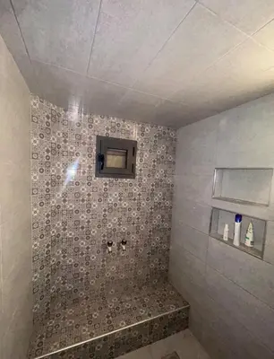 a bathroom with a shower with a tiled wall at Havre de paix à la campagne in El Hajeb