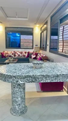 a large marble table in a living room with a couch at Havre de paix à la campagne in El Hajeb