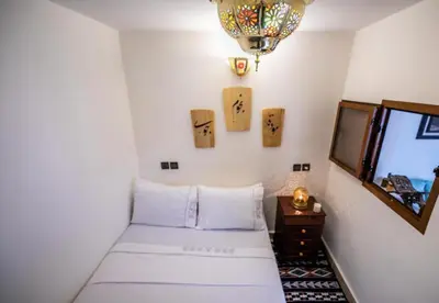 a room with a bed and a television and a chandelier at Dar Yanis in Fès