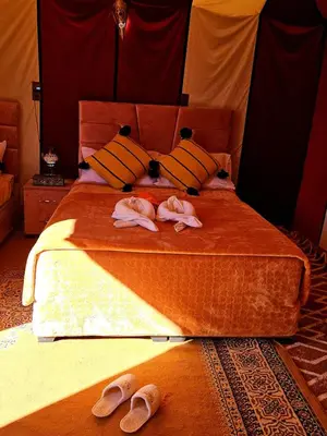 a bedroom with a bed with two slippers on it at Nomad Haven Luxury Camp in Merzouga
