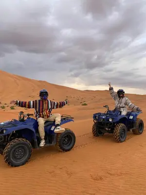 two men riding on atvs in the desert at Nomad Haven Luxury Camp in Merzouga