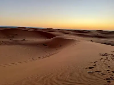 a desert scene with footprints in the sand at Nomad Haven Luxury Camp in Merzouga