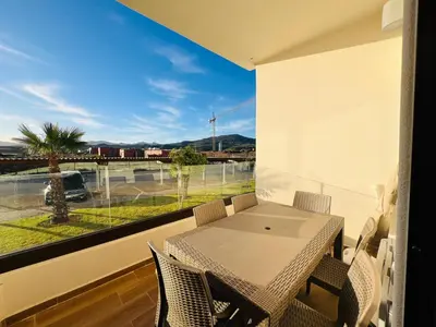 a balcony with a table and chairs and a large window at Colina Smir par Immo Marina Vacances de Rêve D2-4 in Oulad Akkou