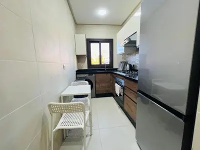 a kitchen with two chairs and a refrigerator at Colina Smir par Immo Marina Vacances de Rêve D2-4 in Oulad Akkou