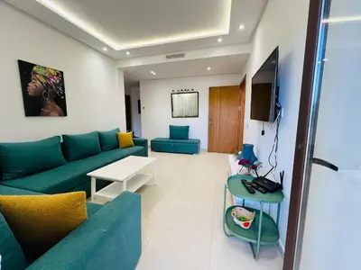 a living room with a blue couch and a table at Colina Smir par Immo Marina Vacances de Rêve D2-4 in Oulad Akkou