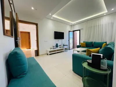 a living room with a blue couch and a tv at Colina Smir par Immo Marina Vacances de Rêve D2-4 in Oulad Akkou