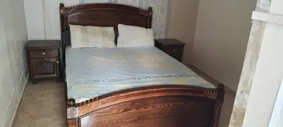 a wooden bed in a bedroom with two night stands at Modern Furnished Apartment in Imouzzer Kandar