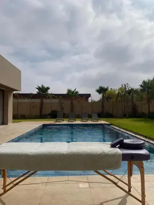 a swimming pool with a bench in front of a building at Villa Madjeyalia Soft Luxury in Marrakech
