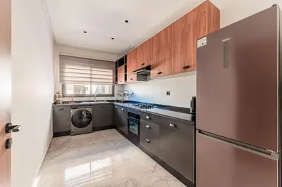 a kitchen with stainless steel appliances and wooden cabinets at Urban Pearl Refined and bright in Oulad Akkou