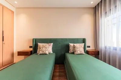 a green couch with two pillows in a room at Urban Pearl Refined and bright in Oulad Akkou