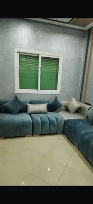 a living room with a blue couch and a window at Spacious apartment in Fès