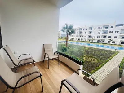 a room with chairs and a balcony with a pool at Colina Smir par Immo Marina Vacances de Rêve D1-3 in Oulad Akkou