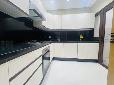 a kitchen with white cabinets and black counter tops at Colina Smir par Immo Marina Vacances de Rêve D1-3 in Oulad Akkou