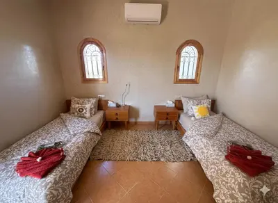 two beds in a room with two windows at Najma Ourika in Ourika