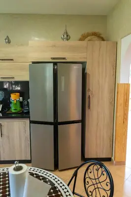 a kitchen with a stainless steel refrigerator and a table at Najma Ourika in Ourika