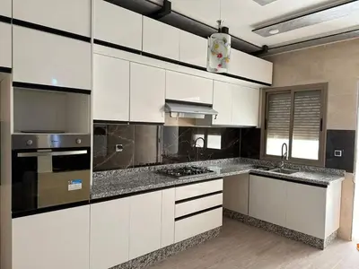 a kitchen with white cabinets and stainless steel appliances at Hote othmane in Beni Mellal