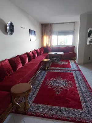a living room with a red couch and a red rug at appartement meublé AGDAL 4chambre in Oulad Akkou