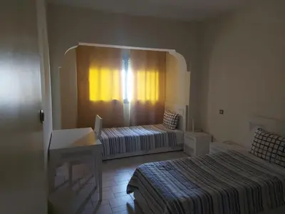 a bedroom with a bed and a window with a desk at appartement meublé AGDAL 4chambre in Oulad Akkou