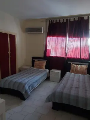 a bedroom with two beds and a red curtain at appartement meublé AGDAL 4chambre in Oulad Akkou