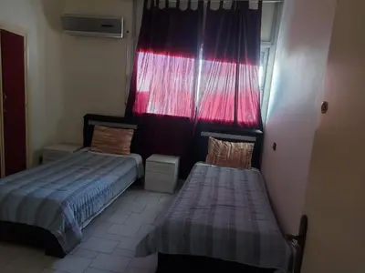 a bedroom with two beds and a red curtain at appartement meublé AGDAL 4chambre in Oulad Akkou