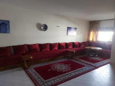 a living room with a red couch and a table at appartement meublé AGDAL 4chambre in Oulad Akkou