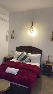 a bedroom with a bed with red sheets and white pillows at Riad fezira in Fès