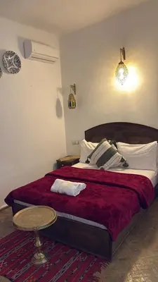 a bedroom with a large bed with red sheets and a table at Riad fezira in Fès