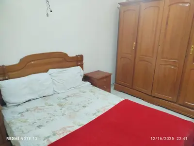 a bedroom with a bed with a red blanket and wooden cabinets at Black iris tadamoune in Meknès