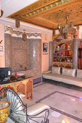 a bedroom with a bed with a wall covered in tiles at Hotel jnane sbille in Fès