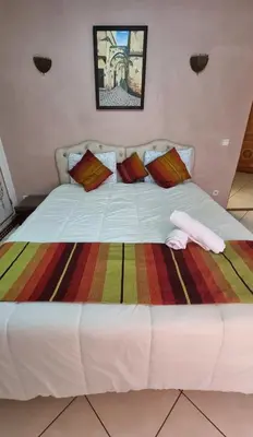 a large white bed with a colorful blanket on it at Hotel jnane sbille in Fès