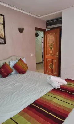 a bedroom with a large bed and a wooden door at Hotel jnane sbille in Fès