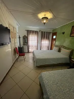 a bedroom with two beds and a red chair at Hotel jnane sbille in Fès