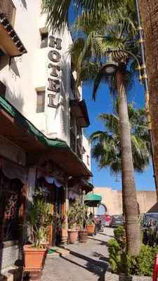 a street with palm trees and a building with a sign at Hotel jnane sbille in Fès