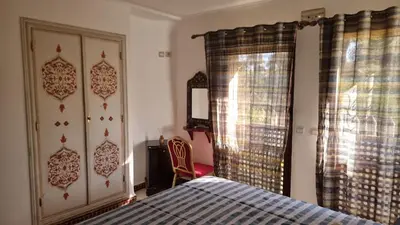 a bedroom with a bed and a chair and a window at Hotel jnane sbille in Fès