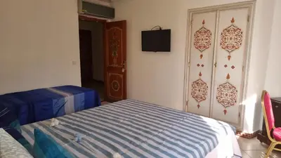 a bedroom with a bed and a tv on the wall at Hotel jnane sbille in Fès