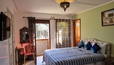 a bedroom with a bed with a blue comforter at Hotel jnane sbille in Fès
