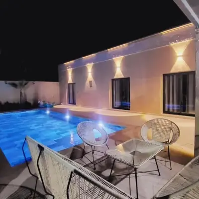a patio with chairs and a swimming pool at night at Bali family villa 0 vis-à-vis in Chouiter
