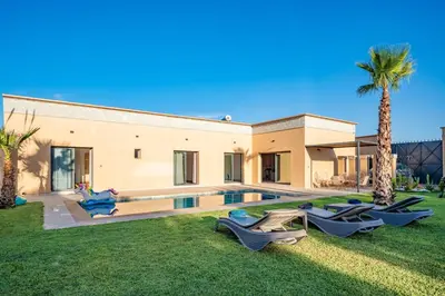 a villa with a swimming pool and palm trees at Bali family villa 0 vis-à-vis in Chouiter