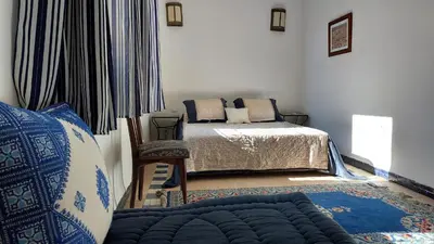a bedroom with two beds and a chair and a window at JNANE RBATI Apartement in Fès